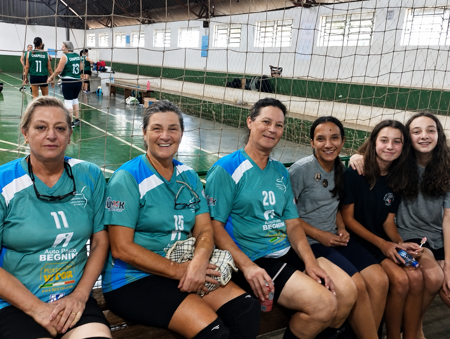 Alunas ao lado de atletas da terceira idade durante o vôlei adaptado
